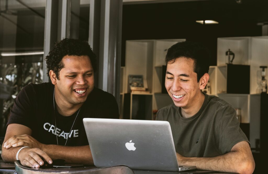 two smiling men looking at MacBook
